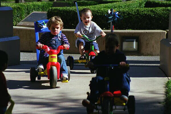 Felix, Adam & Oskar cyklar i lekparken. 2/11 -00.
