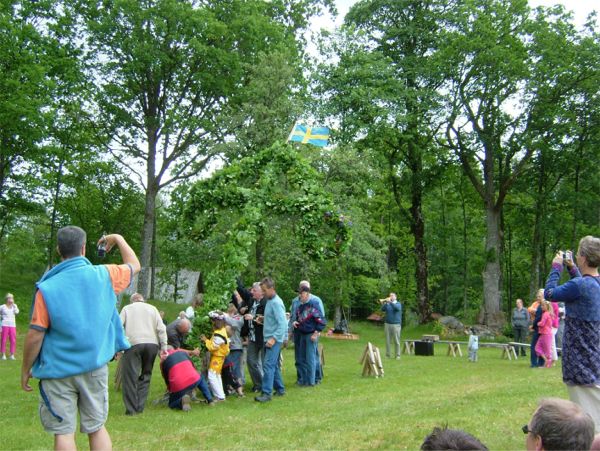 Midsommarstången reses till hornblås (bakgrunden) ...